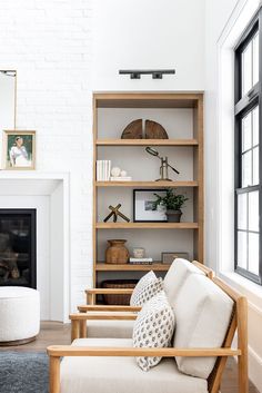 a living room filled with furniture and a fire place in front of a white brick wall