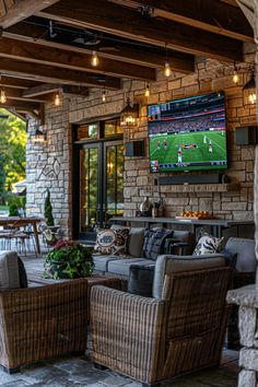 an outdoor living area with wicker furniture and large television on the wall above it