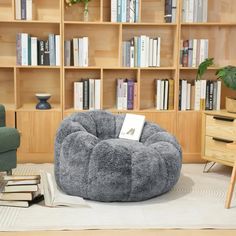 a grey bean bag chair sitting on top of a rug in front of a bookshelf