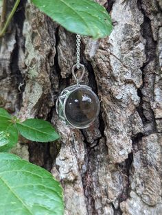 An extra large 20mm crystal clear quartz, tension set in a sterling silver, filigree, crescent moon shaped pendant.   The pendant is polished to a bright, shiny finish. Arrives with the pictured, 24 inch sterling silver rolo chain.  The 8th picture shows the filigree back of the mount. The chain shown is the chain that is included.   There has been no drilling or marring of the quartz whatsoever. The whole quartz sphere is what gives the piece its authenticity. Undrilled whole orbs are the hallm Silver Moon Phase Crystal Necklace, Silver Round Crystal Necklaces Mystical Style, Silver Round Crystal Necklace With Moon Charm, Silver Crystal Necklace With Moon Charm, Silver Moon Phase Pendant Crystal Necklace, Silver Crystal Moon Phase Pendant Necklace, Sterling Silver Moon Phase Pendant Crystal Necklace, Silver Pendant Crystal Necklace With Moon Phase, Sterling Silver Pendant Crystal Necklace With Moon Phase