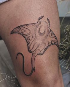 a black and white photo of a tattoo with a stingfish on it's leg