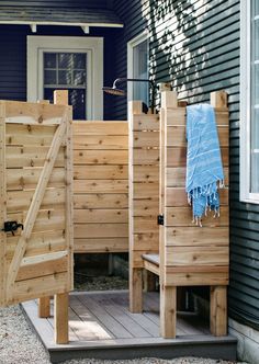 a wooden bench sitting next to a blue house with a towel hanging on it's back