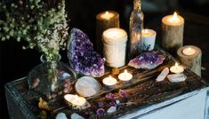 candles, rocks and crystals are arranged on a wooden table with stars in the background