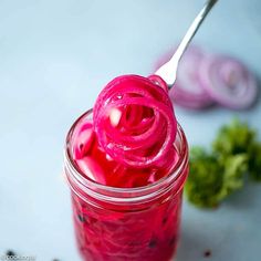 a jar filled with pickled red onions on top of a table next to broccoli