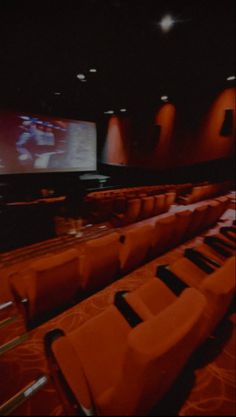 an empty auditorium with rows of seats and a projector screen in the back ground