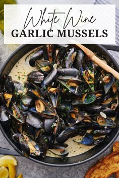 white wine and garlic mussels in a pan with lemon wedges