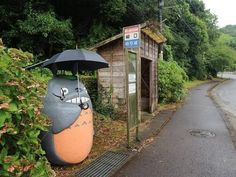 a small wooden building with an umbrella in the shape of a cat on it's head