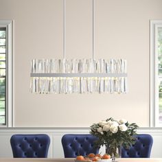 a dining room table with blue chairs and a chandelier hanging from the ceiling