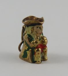 This is a vintage "Enamel Toby Jug" 9 karat gold charm for a charm bracelet. The Toby jug has white hair, green jacket, red pants, black hat and boots and peach skin enamel. *enamel rubbed off* It weighs 2.80 grams and measures 1/2" x 5/8", marked "9, 375" All charms come with a split ring to attach to a bracelet. We have hundreds of charms in stock. If you don't see what you are looking for in our shop please contact us as it is likely we have it. Inventory #G5382 Antique Brass Charms For Collectors, Antique Miniature Gold Jewelry, Antique Gold Charms For Collectors, Red Pants, Black Hat, Split Ring, Gold Charm, White Hair, Green Jacket