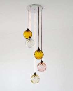 three different colored glass balls hanging from a ceiling light fixture in a white walled room