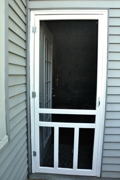 an open door on the side of a house that is white and has glass panels