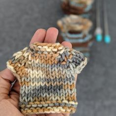 a person holding up a knitted item in their left hand and another object in the background