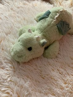 a green stuffed animal laying on top of a white rug in the shape of a dragon