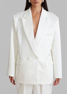 Color: Ivory Classic satin sheen suiting fabric Relaxed silhouette Peak lapels Padded shoulders Single breast pocket Front flap pockets Single front button closure Lined 100% Polyester Dry Clean By The Frankie Shop. Imported Classic Satin Outerwear With Suit Collar, Classic Single-breasted Satin Blazer, White Structured Single-button Blazer, Business Satin Outerwear With Lapel Collar, Classic Satin Blazer With Hidden Buttons, Classic Satin Blazer With Lapel Collar, Classic Satin Blazer With Hidden Button Closure, Satin Single-breasted Business Blazer, Satin Single Breasted Business Blazer