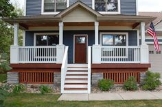 a blue house with white railings and a flag on the front porch is shown