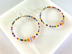 Bright multicolored African beads, Czech beads and seed beads are beaded onto 40mm silver plated hoop dangles and secured with permanent adhesive. They are secured to sterling silver French wires. Brighten up your day with these fun swingy earrings. Playful Multicolor Hoop Jewelry, Sterling Silver Multicolor Beaded Bracelets, Handmade Multicolor Playful Hoop Earrings, Playful Handmade Multicolor Hoop Earrings, Playful Multicolor Handmade Hoop Earrings, Handmade Multicolor Heishi Beads Hoop Earrings, Handmade Multicolor Hoop Earrings With Heishi Beads, Fun Colorful Beaded Round Earrings, Festival Colorful Beaded White Hoop Earrings