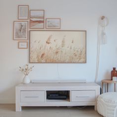 a living room with white furniture and pictures on the wall