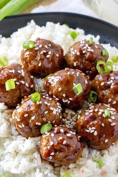 meatballs with sesame seeds and green onions on top of rice in a black bowl