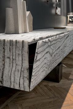 a white marble table with black metal legs and an abstract sculpture in the center, on a wood floor