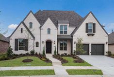 a white house with black shutters and landscaping