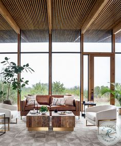 a living room filled with furniture and lots of large windows next to a wooden ceiling