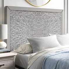 a bedroom with a bed, nightstand and mirror on the wall next to it's headboard