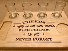 four shot glasses sitting on top of a wooden tray that says cheers and friends with friends we will never forget