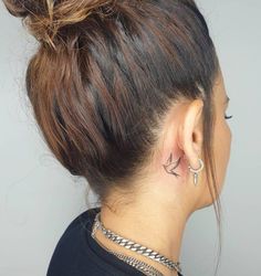 the back of a woman's head with a tattoo on her left side ear