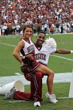 a man and woman in cheerleader outfits posing for a photo on the football field