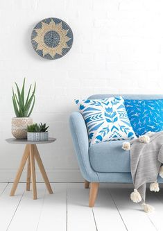 a blue couch sitting next to a table with a potted plant on it