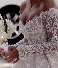 a woman in a wedding dress holding a bouquet of white flowers and looking at the camera