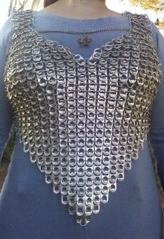 a woman wearing a blue top with silver chains on it's chest and back