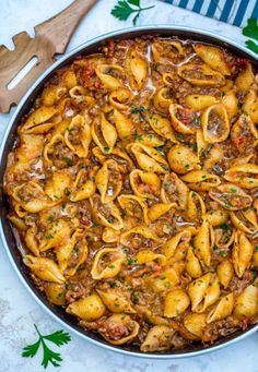 pasta with meat and sauce in a pan on a table next to wooden utensils