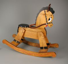 a wooden rocking horse with black and red trimmings on it's face