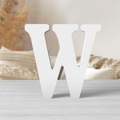 the letter w is made out of white plywood and stands on a wooden table