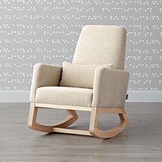 a wooden rocking chair in front of a wall with white and gray designs on it