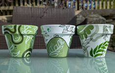 three green cups sitting on top of a table next to a brown and white chair