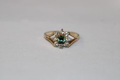 SKU: 0179 A beautiful green and white cubic zirconia fancy ring set in 9ct yellow gold. This pretty ring would be perfect for any and every occasion. Size: UK: P American: 7 1/2 Continental: 16 This is a vintage item and such has wear. There may be some superficial scratches, otherwise the item is good condition. This item comes beautifully boxed in our own packaging. Processing time for orders is 1-3 business days. Classic Green Cubic Zirconia Cluster Ring, Green 14k Gold Cluster Ring For Anniversary, Anniversary 14k Gold Green Cluster Ring, Anniversary Green Cubic Zirconia Birthstone Ring, Green Brilliant Cut Cluster Ring For Anniversary, 14k Gold Green Cluster Ring With Accent Stones, Green 14k Gold Cluster Ring With Accent Stones, Green Cubic Zirconia Cluster Ring With Halo Setting, Green Sapphire Ring In 14k Gold For Anniversary