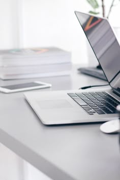 an open laptop computer sitting on top of a desk next to a stack of books