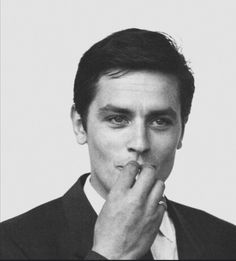 a black and white photo of a man with his finger in his mouth