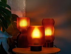 three lamps sitting on top of a table next to a potted plant