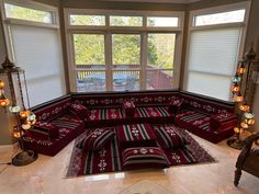 a living room filled with lots of red couches and pillows on top of each other