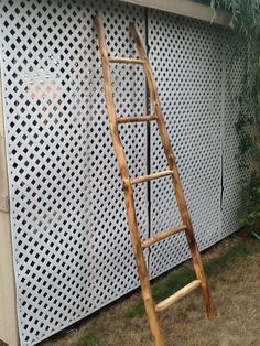 a wooden ladder leaning against a white perfored wall in front of a house