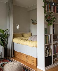 a bed sitting next to a book shelf filled with books on top of a wooden floor