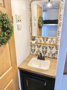 a bathroom sink with a mirror above it and a door leading to the toilet area