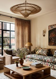 a living room filled with furniture and a painting hanging on the wall above it's windows