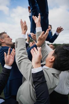 a group of people in suits and ties holding their hands up