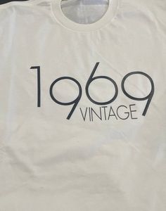 White T-Shirt "Vintage 1969" Classic Graphic Print T-shirt For Birthday, Vintage White T-shirt For Birthday, Retro White Tops For Anniversary, Classic Letter Print T-shirt For Anniversary, Vintage Letter Print Tops For Anniversary, Vintage White Top For Birthday, Retro Graphic Print Tops For Anniversary, Vintage Short Sleeve Tops For Birthday, Vintage Text Print Top For Birthday