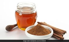 cinnamon sticks and honey in a white bowl next to a glass jar filled with liquid