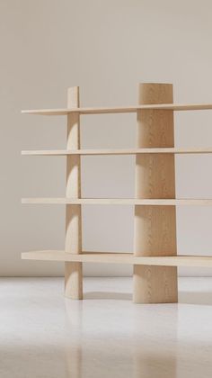 two wooden bookshelves sitting on top of a white floor next to each other